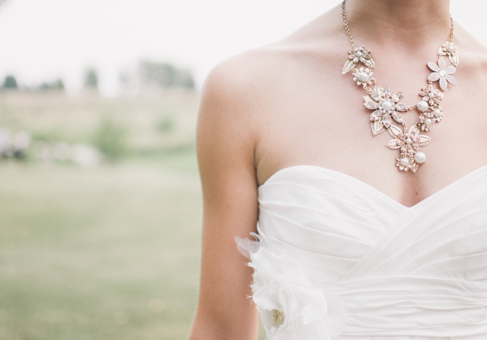 a bride on a white gown wearing a pearl flower necklace